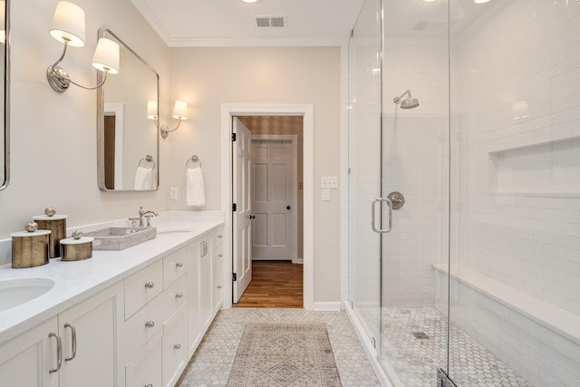 full bath featuring double vanity, a stall shower, visible vents, ornamental molding, and a sink