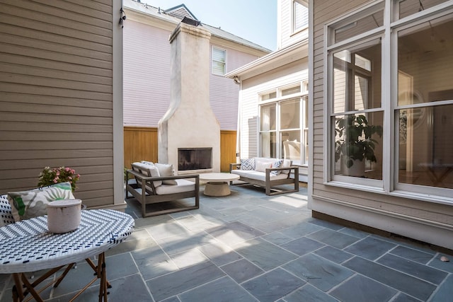 view of patio / terrace with an outdoor living space with a fireplace and fence