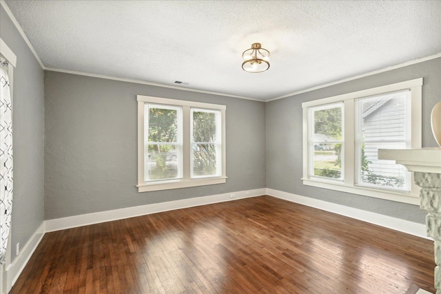 spare room featuring plenty of natural light, ornamental molding, hardwood / wood-style flooring, and a fireplace