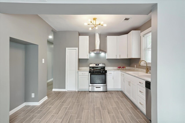 kitchen with white cabinets, appliances with stainless steel finishes, wall chimney exhaust hood, and sink