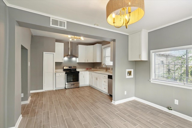 kitchen featuring light wood-type flooring, appliances with stainless steel finishes, a chandelier, sink, and wall chimney exhaust hood