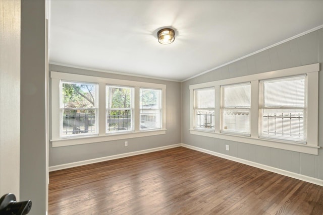 empty room featuring lofted ceiling, dark hardwood / wood-style floors, crown molding, and a healthy amount of sunlight