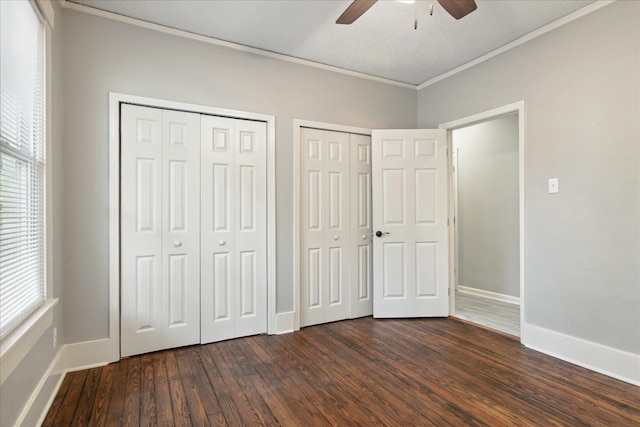 unfurnished bedroom with multiple closets, multiple windows, ceiling fan, and dark hardwood / wood-style floors