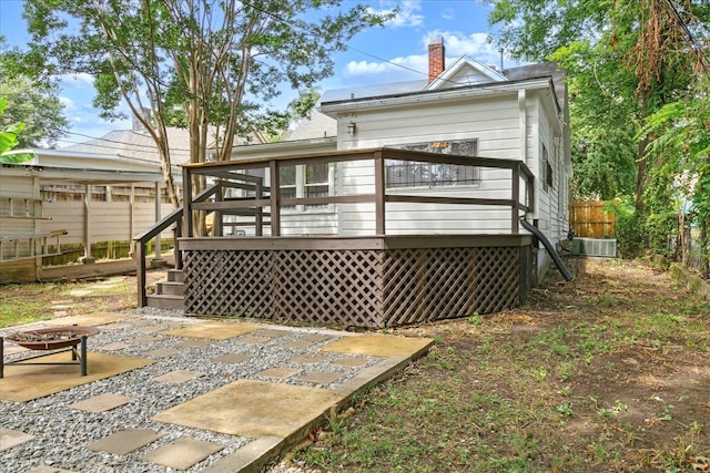 rear view of property featuring a fire pit, cooling unit, a patio, and a deck