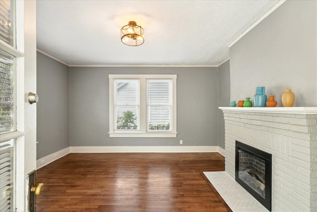 unfurnished living room featuring a textured ceiling, ornamental molding, a brick fireplace, and dark hardwood / wood-style flooring