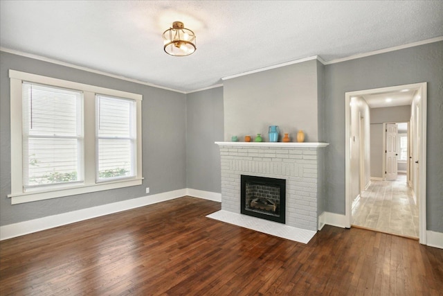 unfurnished living room with crown molding, dark hardwood / wood-style flooring, a brick fireplace, and a textured ceiling