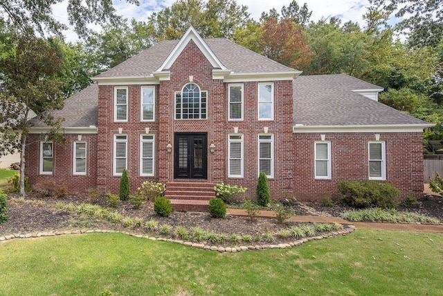 view of front of home with brick siding, french doors, and a front lawn