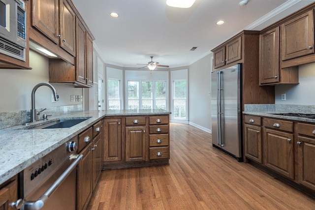 kitchen featuring wood finished floors, visible vents, a sink, stainless steel appliances, and crown molding