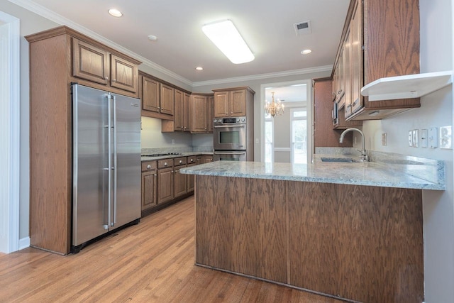 kitchen featuring visible vents, ornamental molding, a sink, stainless steel appliances, and a peninsula