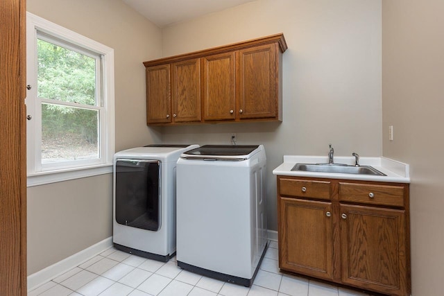 laundry area featuring baseboards, light tile patterned flooring, cabinet space, a sink, and independent washer and dryer