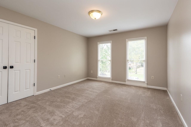 empty room featuring visible vents, baseboards, and carpet floors