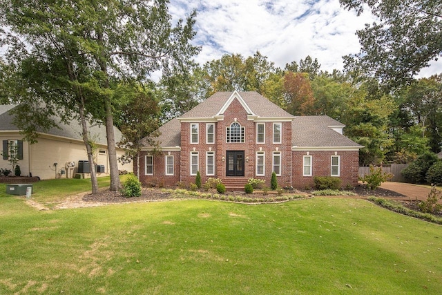 view of front of house with cooling unit, brick siding, and a front yard