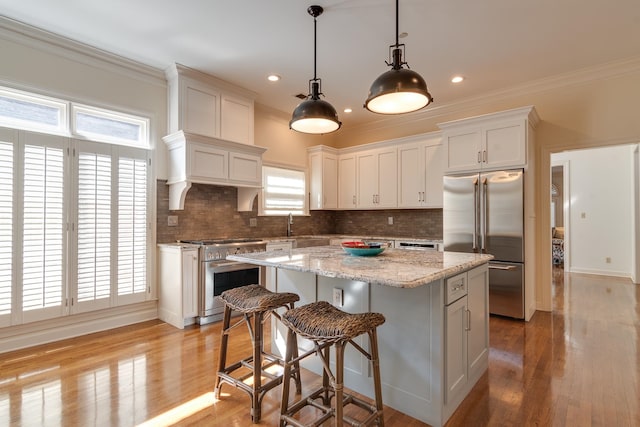 kitchen featuring high end appliances, light hardwood / wood-style floors, white cabinetry, and a kitchen island