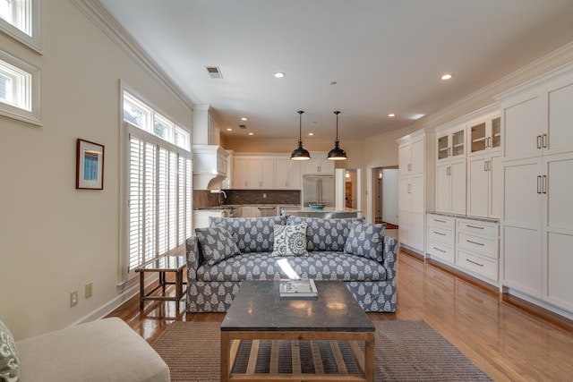 living room featuring crown molding, wood-type flooring, and sink