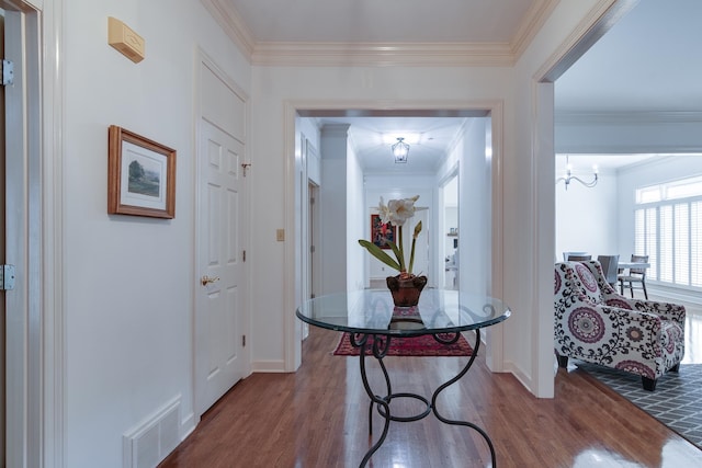 hall featuring hardwood / wood-style floors, a notable chandelier, and ornamental molding