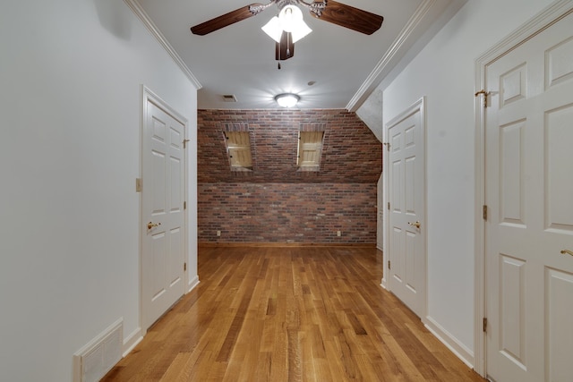 corridor with crown molding, brick wall, and light hardwood / wood-style flooring