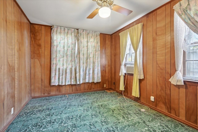 spare room with ceiling fan and wood walls