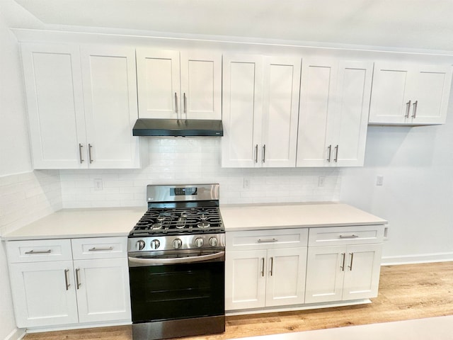 kitchen with light wood-type flooring, decorative backsplash, stainless steel gas range oven, and white cabinetry