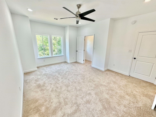 empty room with ceiling fan and light carpet