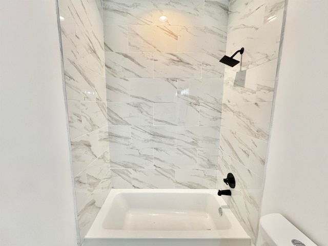 bathroom featuring tiled shower / bath combo and toilet