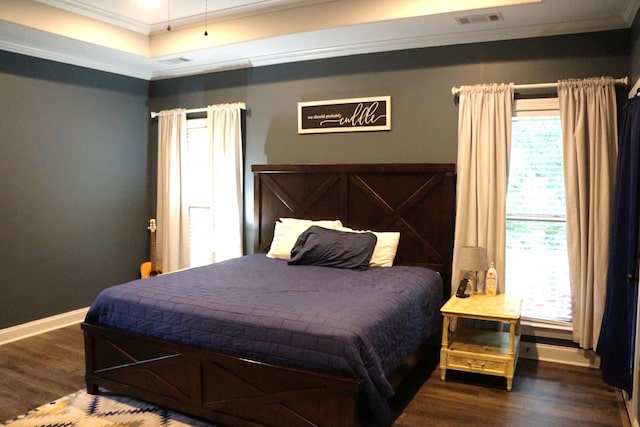 bedroom with dark wood-type flooring, ornamental molding, and a raised ceiling