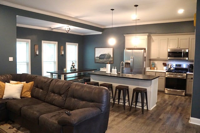 kitchen with hanging light fixtures, stainless steel appliances, dark hardwood / wood-style floors, white cabinets, and a center island with sink