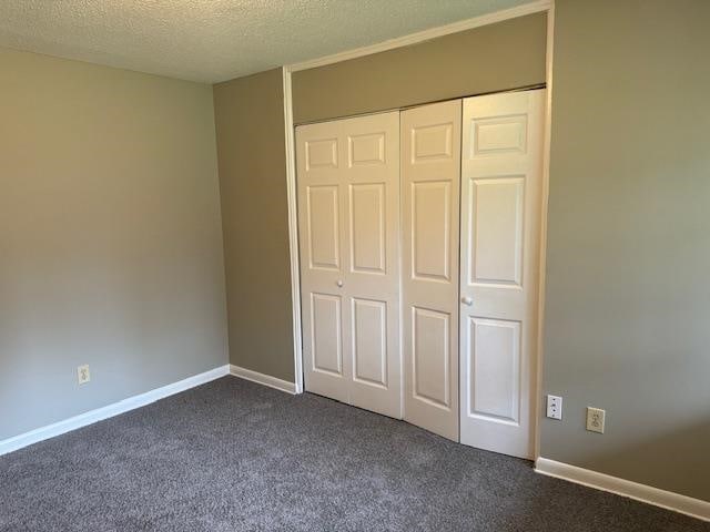 unfurnished bedroom featuring a closet, a textured ceiling, and carpet floors