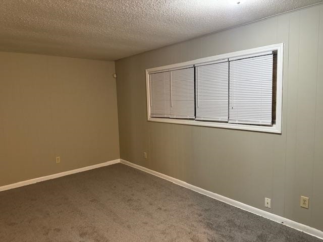 empty room featuring a textured ceiling and dark colored carpet