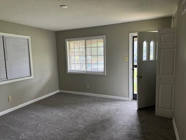 foyer featuring a textured ceiling and dark carpet