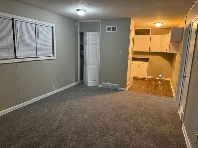 interior space with a textured ceiling and carpet flooring