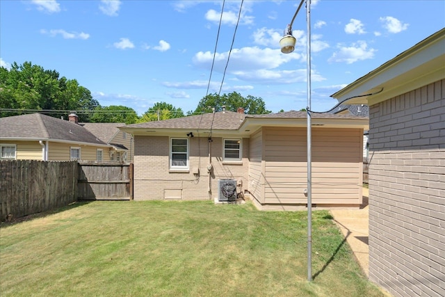 back of property with central air condition unit and a yard