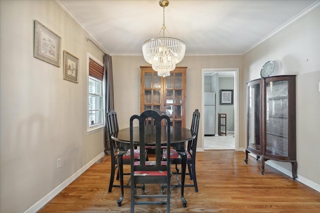 dining area featuring ornamental molding, a notable chandelier, and light hardwood / wood-style flooring