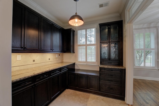 kitchen featuring decorative light fixtures, a wealth of natural light, and crown molding