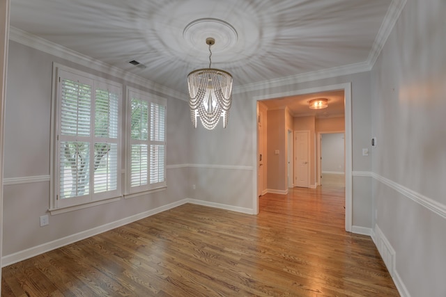 unfurnished dining area with hardwood / wood-style floors, ornamental molding, and a notable chandelier