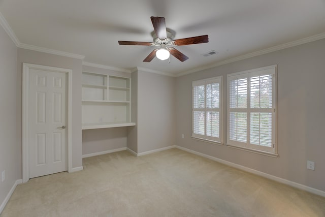 unfurnished bedroom featuring ceiling fan, built in desk, ornamental molding, and light carpet