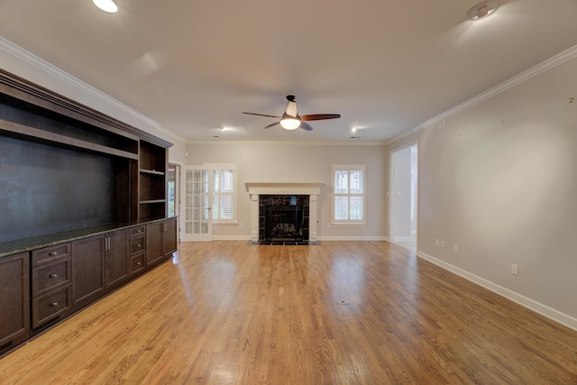 unfurnished living room with a fireplace, light hardwood / wood-style flooring, ceiling fan, and crown molding