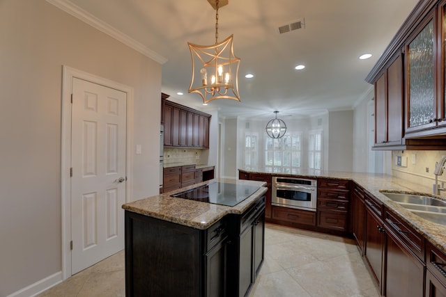 kitchen featuring a center island, crown molding, a chandelier, decorative light fixtures, and black electric stovetop