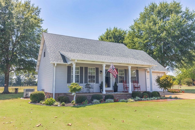 view of front facade featuring a porch, a garage, a front lawn, and central AC