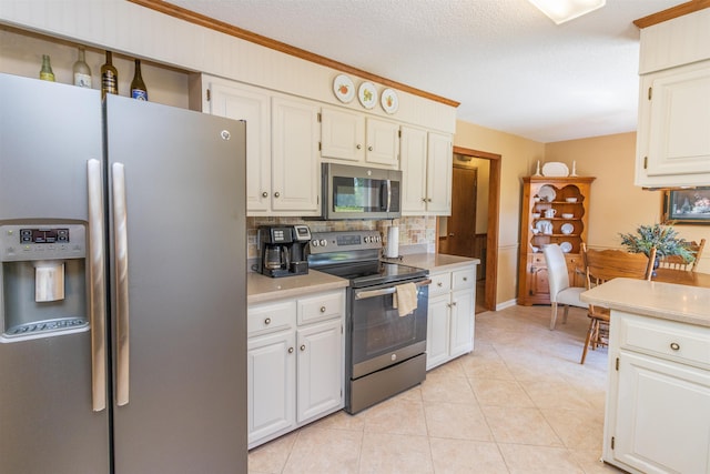 kitchen featuring light tile patterned floors, appliances with stainless steel finishes, white cabinetry, and decorative backsplash