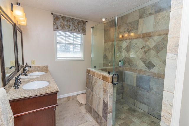 bathroom with a textured ceiling, vanity, and an enclosed shower