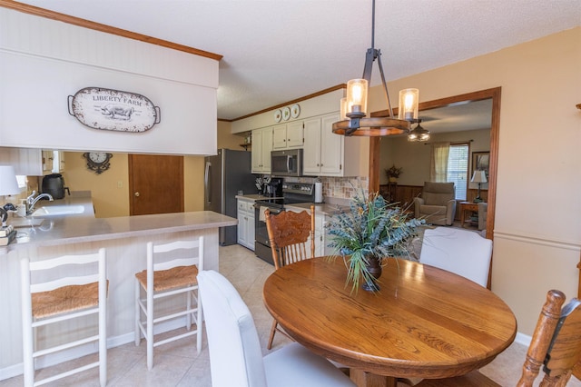 dining area featuring crown molding, a textured ceiling, a chandelier, sink, and light tile patterned flooring