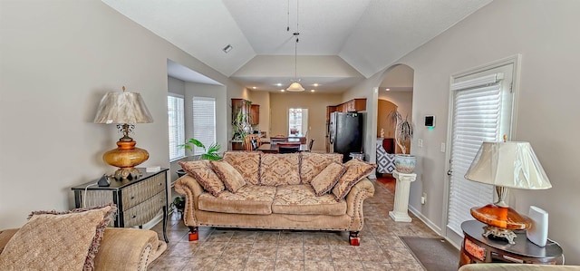 living area featuring lofted ceiling, visible vents, arched walkways, and baseboards