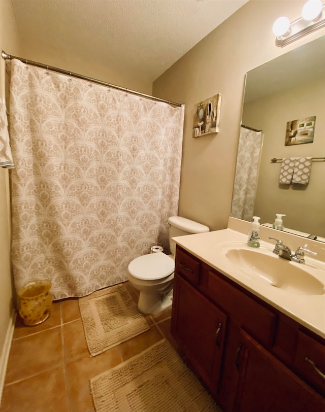 bathroom with a textured ceiling, vanity, toilet, and tile patterned floors