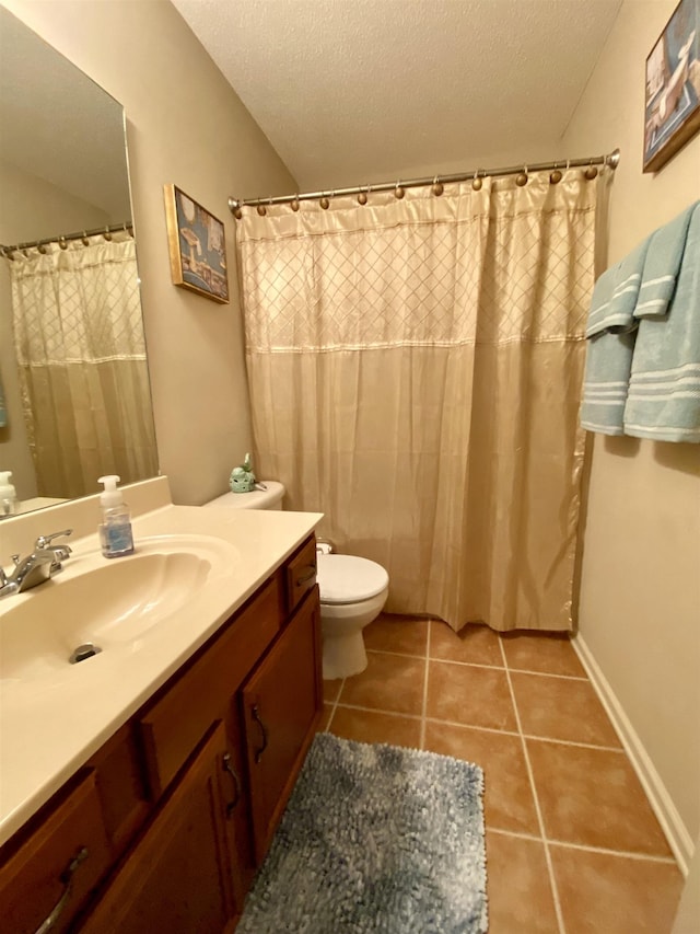 bathroom with a textured ceiling, toilet, tile patterned flooring, and vanity