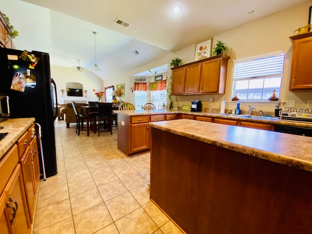 kitchen with light tile patterned floors, vaulted ceiling, kitchen peninsula, black fridge, and ceiling fan