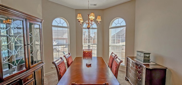 dining room featuring baseboards, carpet, visible vents, and a notable chandelier