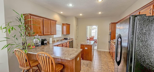 kitchen featuring dishwasher, a kitchen island, freestanding refrigerator, a peninsula, and a sink