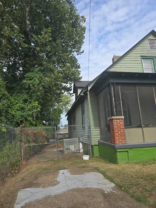 view of side of property featuring a sunroom and a lawn