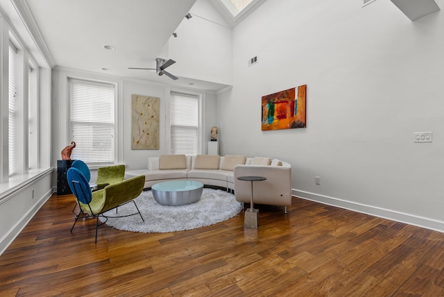 living area with baseboards, visible vents, a skylight, ceiling fan, and hardwood / wood-style flooring