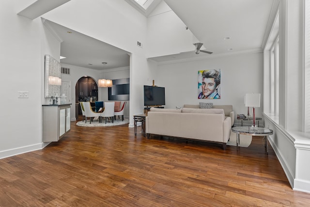 living room with arched walkways, ornamental molding, baseboards, and dark wood-style flooring